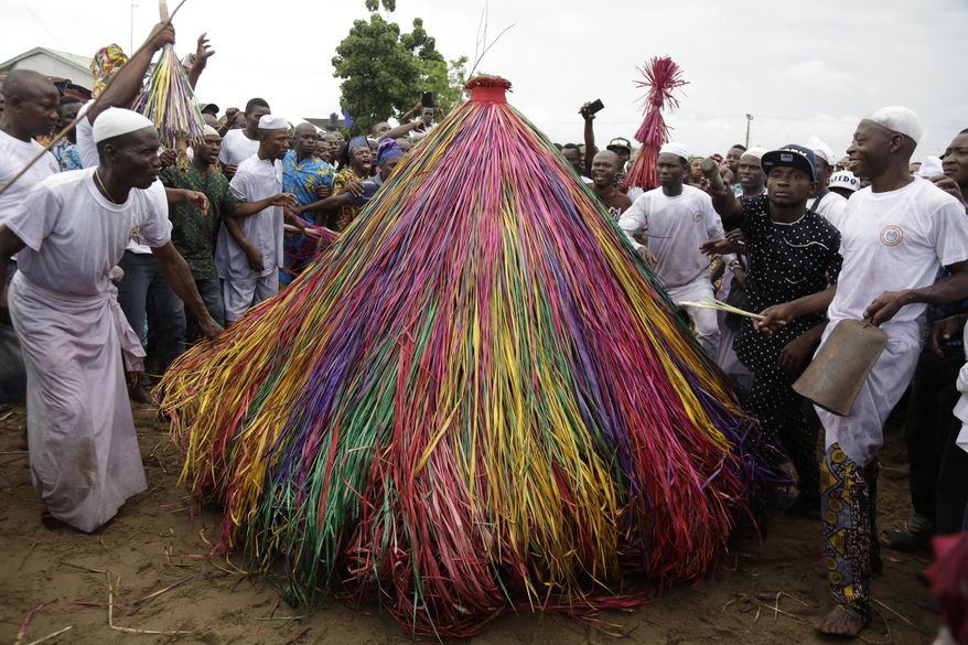 In this photo taken Saturday, Sept. 22, 2018, masquerades known as Zangbeto dressed in costumes, parade the street to mark the Ajido Voodoo festival in Nigeria. Excitement grew in the crowd as the Zangbeto Voodoo festival reached a climax, with scores of colorful palm-frond figures representing the traditional guardian of the night. (AP Photo/Sunday Alamba)