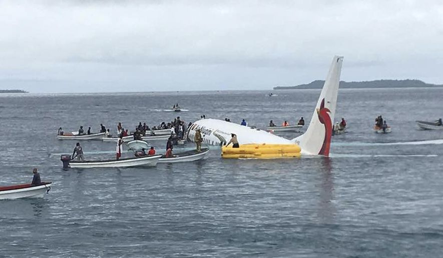 Local fishing boats move in to recover the passengers and crew of Air Niugini flight following the plane crashing into the sea on its approach to Chuuk International Airport in the Federated States of Micronesia., Friday, Sept. 28, 2018. All 47 passengers and crew survived a plane's crash landing in a Pacific lagoon Friday morning, wading through waist-deep water to the emergency exits and escaping on local boats that came to the rescue in the Micronesia archipelago. (James Yaingeluo via AP)