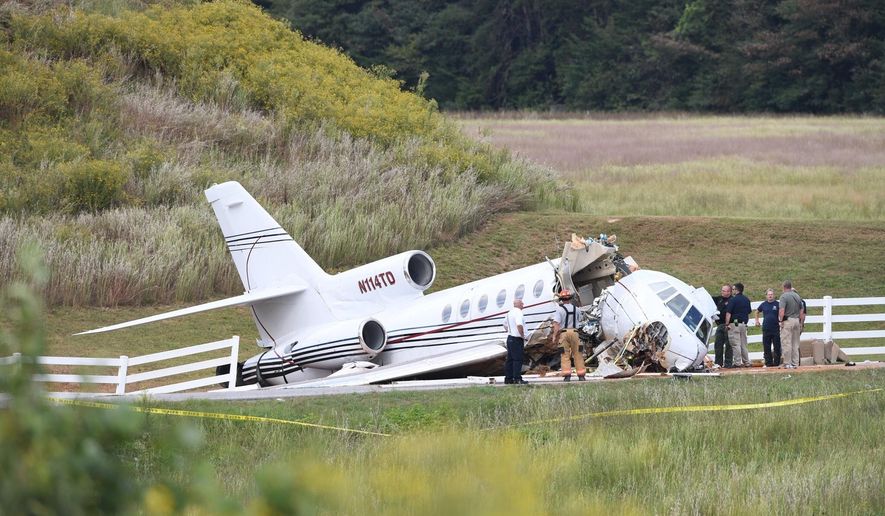 Emergency personnel responding after an aircraft crashed onto Airport Road in Greenville, S.C. The mid-sized jet that tried to land at a South Carolina airport and ran off the runway and split in two, killing the two pilots on board and injuring two passengers. Witnesses say the plane appeared to land without a problem until it overshot the runway and went down a steep embankment. (Bart Boatwright/The Greenville News via AP)