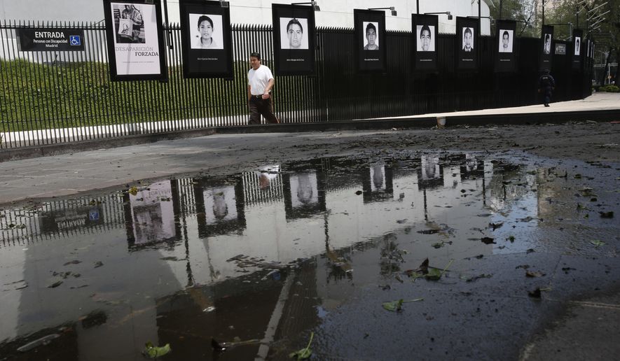 In this Sept. 26, 2018 photo, photographs of the teachers college students who disappeared on Sept. 26, 2014 hang on the fence surrounding the Senate building in Mexico City. President-elect Andres Manuel Lopez Obrador said Wednesday his administration will accept a truth commission to investigate the case of the 43 missing students, drawing rare praise and expressions of hope from the long-suffering parents of the victims. (AP Photo/Rebecca Blackwell)
