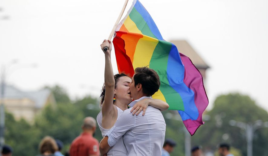 FILE - In this Saturday, June 9, 2018 file photo, two girls kiss holding a rainbow flag during the gay pride parade in Bucharest, Romania. Romania's top court has ruled that gay couples should have the same family rights as heterosexuals, a judgment that comes before a referendum seeking to ban same-sex marriage. The Constitutional Court has ruled that same-sex couples have the same rights to a private and family life as heterosexuals. Teodora Ion-Rotaru, of the gay rights group Accept, told The Associated Press on Friday, Sept. 28 the ruling was "extremely important." (AP Photo/Vadim Ghirda, file)