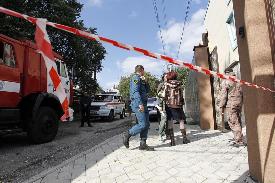 Police and experts work at the side of the blast in Donetsk, capital of the Donetsk region where Russia-backed separatists have been fighting Ukrainian forces since 2014, Ukraine, Saturday, Sept. 29, 2018. Officials in one of Ukraine's separatist regions say three people have been wounded in an explosion at a meeting of the local Communist Party. (AP Photo/Alexander Yermochenko)