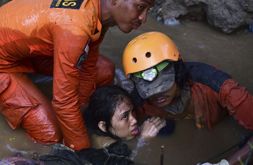 Rescuers evacuate an earthquake survivor by a damaged house following earthquakes and tsunami in Palu, Central Sulawesi, Indonesia, Sunday, Sept. 30, 2018. Rescuers were scrambling Sunday to try to find trapped victims in collapsed buildings where voices could be heard screaming for help after a massive earthquake in Indonesia spawned a deadly tsunami two days ago. (AP Photo/Arimacs Wilander)