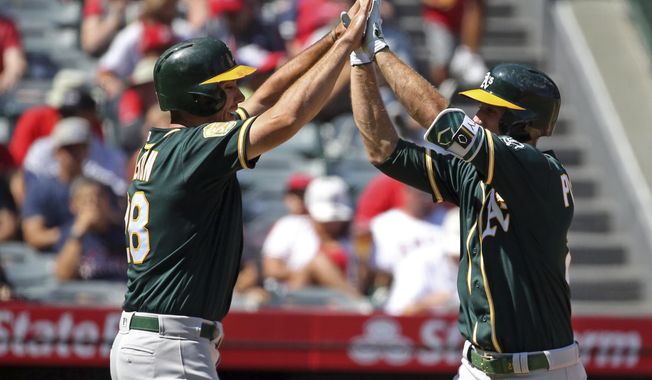 Oakland Athletics Stephen Piscotty, right, and Matt Olson celebrate as both score on Piscotty&#x27;s home run against the Los Angeles Angels in the second inning of a baseball game in Anaheim, Calif., Sunday, Sept. 30, 2018. (AP Photo/Reed Saxon)