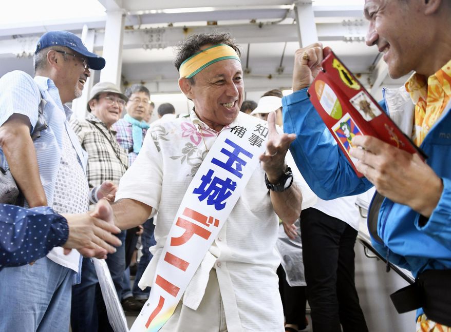 In this Sept. 28, 2018, photo, Denny Tamaki, a legislator, center shakes hands with supporters during his election campaign for Okinawa governor in Naha city. Okinawans are choosing a governor in an election Sunday, Sept. 30, that many see hinging on how voters feel about the American military presence on the southwestern Japanese island.(Koji Harada/Kyodo News via AP)