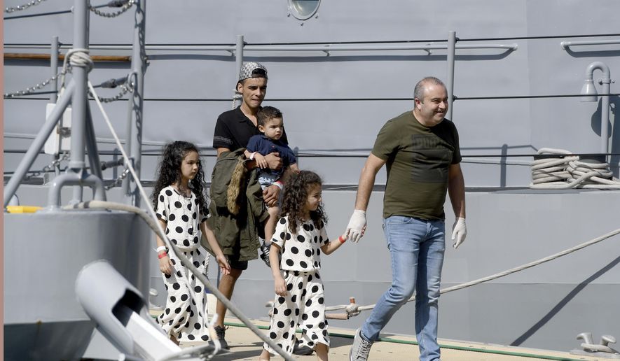 A family is assisted as it disembarks from a Maltese naval vessel in the port of La Valletta in Malta after being transferred from a humanitarian ship which rescued them at sea over a week ago, Sunday, Sept. 30, 2018. The Maltese government said Sunday that the migrants would be then transferred in the coming days to the four countries agreeing to accept them: France, Germany, Spain and Portugal. (AP Photo/Jonathan Borg)
