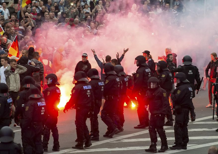 FILE - In this Aug. 27, 2018 photo protesters light fireworks during a far-right demonstration in Chemnitz, Germany. German prosecutors say they have ordered the arrest of six men on suspicion of forming a "far-right terrorist organization" in the eastern city of Chemnitz, where anti-migrant violence flared this summer. Prosecutors said in a statement the men planned to carry out armed attacks against foreigners and political enemies. (AP Photo/Jens Meyer, file)