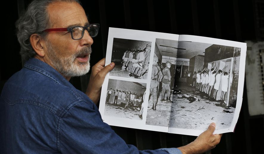 In this Sept. 18, 2018 photo, Enrique Espinosa shows a magazine photo in which he and other demonstrators are being detained by armed soldiers during the Tlatelolco massacre in Mexico City. As Mexico marks 50 years since the killings of student protesters at Tlatelolco plaza, the massacre remains an open wound. (AP Photo/Marco Ugarte)