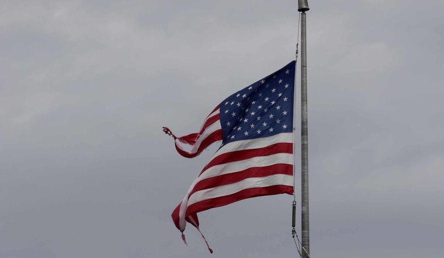 FILE - This Sept. 16, 2018, file photo shows a tattered American flag after Hurricane Florence in Jacksonville N.C. The U.S. flag that captured attention nationwide as it whipped in the wind on the North Carolina coast during Hurricane Florence is being auctioned to raise money for the American Red Cross. (AP Photo/Tom Copeland, File)