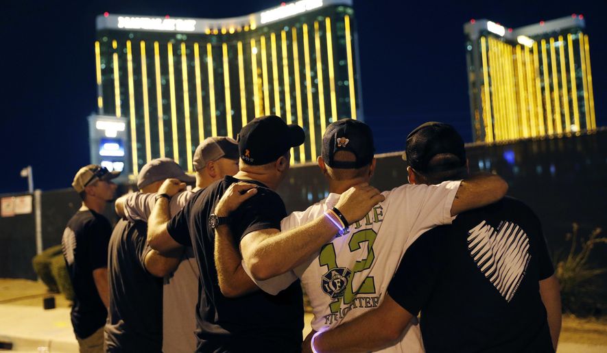 Survivors return to the scene of a mass shooting on the first anniversary, Monday, Oct. 1, 2018, in Las Vegas. Hundreds of survivors of the Las Vegas mass shooting have formed a human chain around the shuttered site of a country music festival where a gunman opened fire last year. (AP Photo/John Locher)