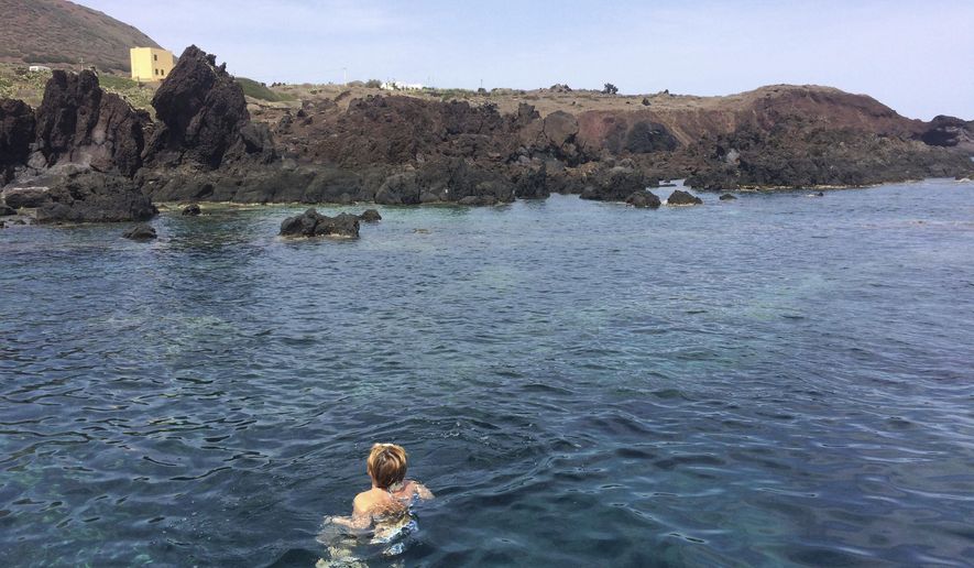 In this photo taken on Sunday, Sept. 9, 2018 a woman swims in a cove of pristine water surrounded by volcanic rock formations on the island of Linosa, some 167 km (103.5 miles) south of Sicily, southern Italy. (AP Photo/Frances D'Emilio)