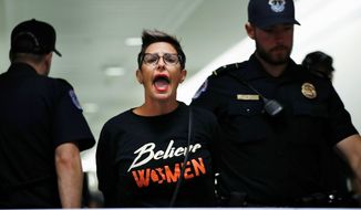 A woman protesting Supreme Court nominee Brett M. Kavanaugh is removed from the hallway.
