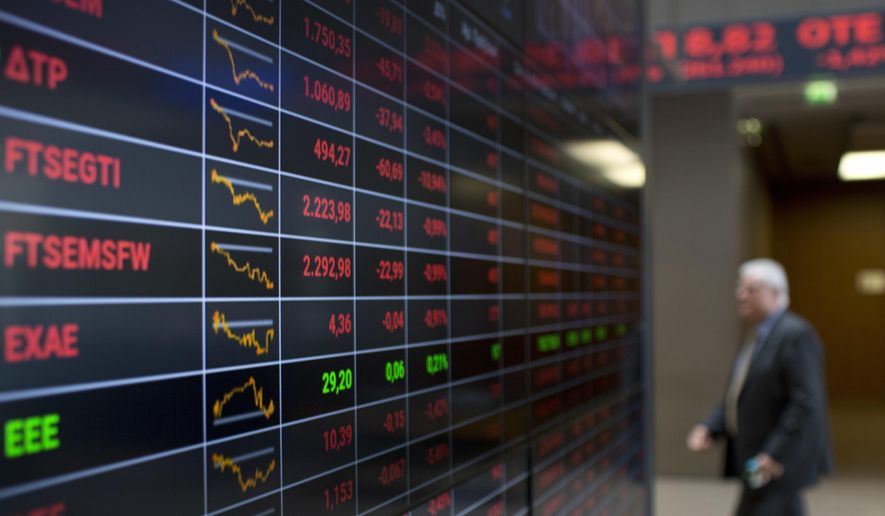 An employee of Athens Stock Exchange walks past screens showing falling stocks in red, in Athens, Wednesday, Oct. 3, 2018. Greek banking shares are down sharply amid investor fears over the lenders' needs to reduce their large stock of bad loans resulting from the financial crisis. The index of bank stocks was down 10 percent in Athens on Wednesday amid reports that some of the bigger banks plan to more aggressively write off bad loans. (AP Photo/Petros Giannakouris)