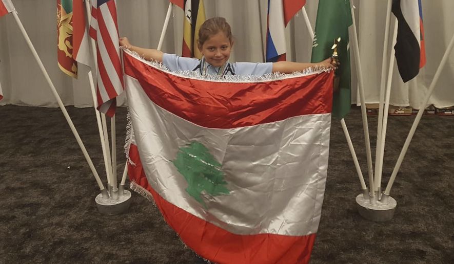 This Sept. 30, 2018 photo provides by Rochana Atmeh, shows Jennifer Maria Hektor, 8, born to a Swedish father and Rochana Atmeh, her Lebanese mother, holding a Lebanese flag, in Johannesburg, South Africa. Hektor won runner-up place in an international mental calculation competition in South Africa representing Lebanon. But the 8-year old doesn't have Lebanese citizenship. Human Rights Watch called on Lebanese authorities to amend a 1925 law that discriminates against Lebanese mothers, denying them the right to pass on citizenship to their children. (Rochana Atmeh via AP)