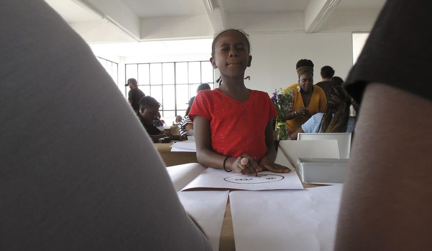 A girl from the Ember Charter School in Brooklyn, N.Y. draws her own face during an art workshop in Johannesburg on Saturday, Sept. 29, 2018. Dozens of students from a Brooklyn charter school are visiting South Africa to explore African cultures and South Africa’s journey from racial tension to reconciliation. (AP Photo/Christopher Torchia)