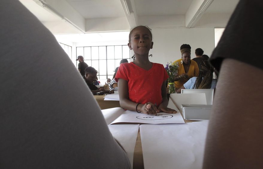 A girl from the Ember Charter School in Brooklyn, N.Y. draws her own face during an art workshop in Johannesburg on Saturday, Sept. 29, 2018. Dozens of students from a Brooklyn charter school are visiting South Africa to explore African cultures and South Africa’s journey from racial tension to reconciliation. (AP Photo/Christopher Torchia)