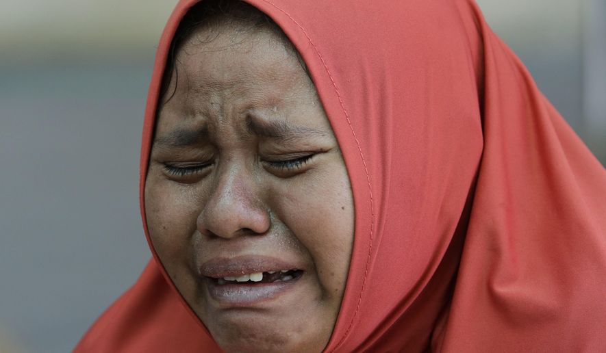 A woman cries after learning that her daughter was one of those buried at a mass grave after being recovered in the massive earthquake and tsunami at Palu, Central Sulawesi, Indonesia Thursday, Oct. 4, 2018. Nearly a week after a magnitude 7.5 quake spawned a deadly tsunami on Indonesia’s island of Sulawesi, countless people have yet to find their loved ones _ both survivors and the dead. As of Thursday, the official death toll was 1,424, with 113 people missing. Many families, though, never registered their losses with police, and others have failed to identify them before they were buried anonymously in mass graves. (AP Photo/Aaron Favila)