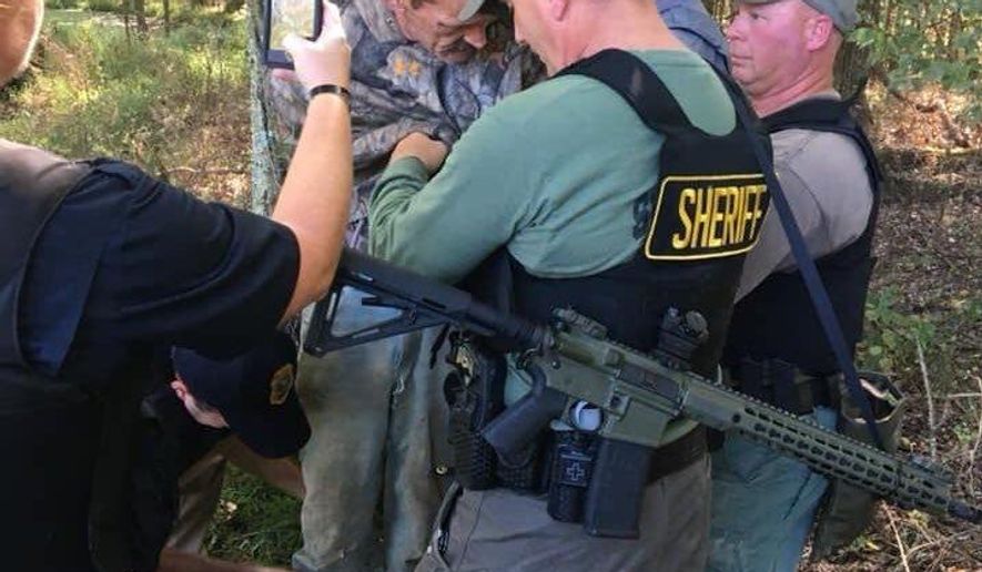 This photo provided by The Tennessee Bureau of Investigation shows law enforcement agents holding Kirby Wallace in custody on Friday, Oct. 5, 2018 in Tennessee. Wallace is wanted on multiple charges after being accused of attacking a couple and setting their house on fire, killing the wife and seriously injuring the husband. He's also accused of fatally shooting a man Monday and stealing his truck. (The Tennessee Bureau of Investigation via AP)