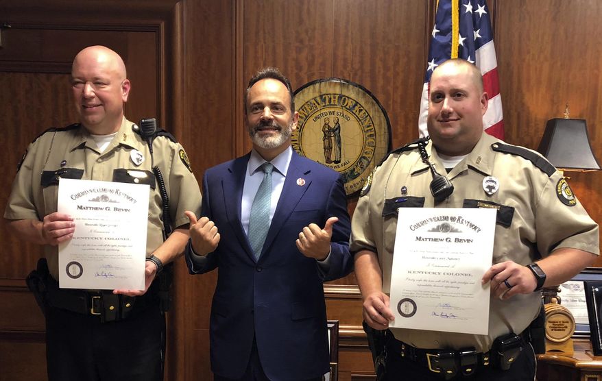 Gov. Matt Bevin, center, poses with Facilities Security Officers Roger Swiger, left, and Casey Mahoney, right, at the state Capitol in Frankfort, Ky., on Friday, Oct. 5, 2018. Bevin awarded both men an honorary commission of Kentucky Colonel for their part in saving the life of Kentucky NAACP President Raoul Cunningham. Cunningham collapsed during a meeting of the State Board of Election in September. Swiger and Mahoney administered CPR and a defibrillator until help arrived. (AP Photo/Adam Beam)