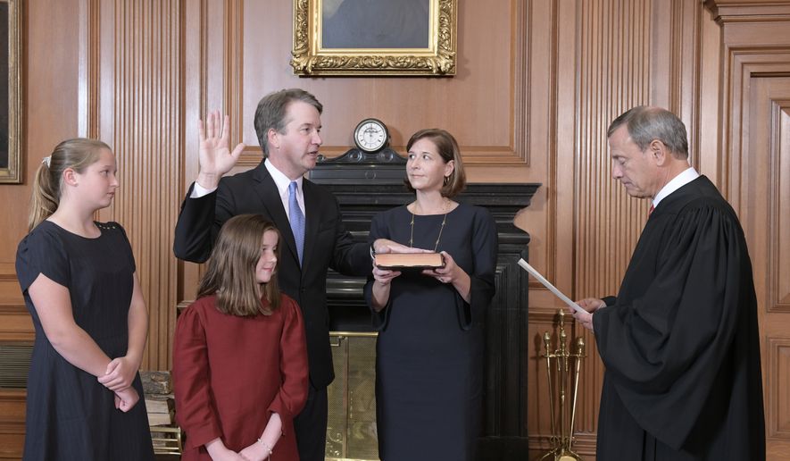 Chief Justice John Roberts, right, administers the Constitutional Oath to Judge Brett Kavanaugh in the Justices&#x27; Conference Room of the Supreme Court Building. Ashley Kavanaugh holds the Bible. In the foreground are their daughters, Margaret, left, and Liza. (Fred Schilling/Collection of the Supreme Court of the United States via AP)