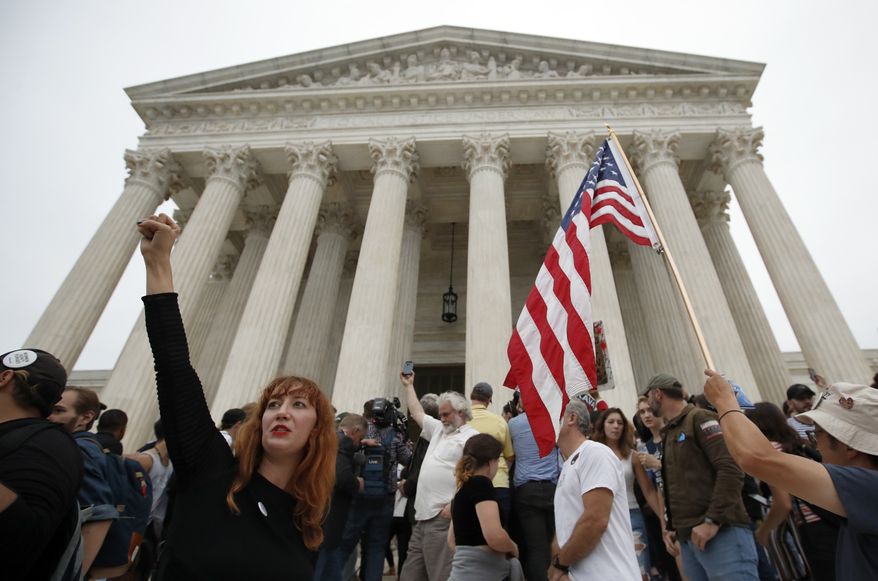 A protester raises her fist as activists protest on the steps of the Supreme Court after the confirmation vote of Supreme Court nominee Brett Kavanaugh, on Capitol Hill, Saturday, Oct. 6, 2018 in Washington. (AP Photo/Alex Brandon)