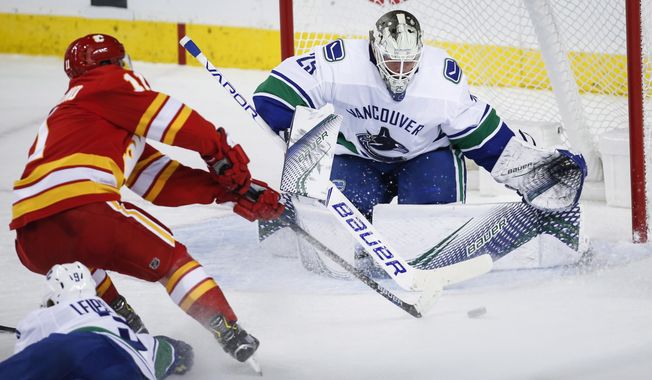 Vancouver Canucks goalie Jacob Markstrom, right, of Sweden, blocks the net on Calgary Flames&#x27; Mikael Backlund, of Sweden, during the second period of an NHL hockey game in Calgary, Alberta, Saturday, Oct. 6, 2018. (Jeff McIntosh/The Canadian Press via AP)