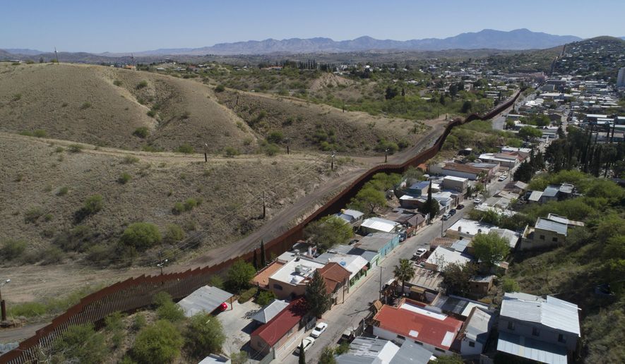 FILE - This April 2, 2017 file photo made with a drone, shows the U.S. Mexico border fence as it cuts through the two downtowns of Nogales, Ariz. The Arizona Attorney General&#39;s Office is seeking more funding to ease the burden brought by a rise in cases at the border. (AP Photo/Brian Skoloff, File)