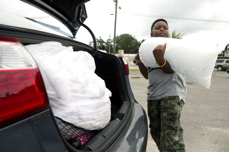 Xavier McKenzie puts a twenty pound bag of ice into his family&#39;s car in Panama City, Fla., as Hurricane Michael approaches on Tuesday, Oct.9, 2018. He and his family do not live in a storm surge area, and instead prepared for losing power for days. (Joshua Boucher/News Herald via AP)