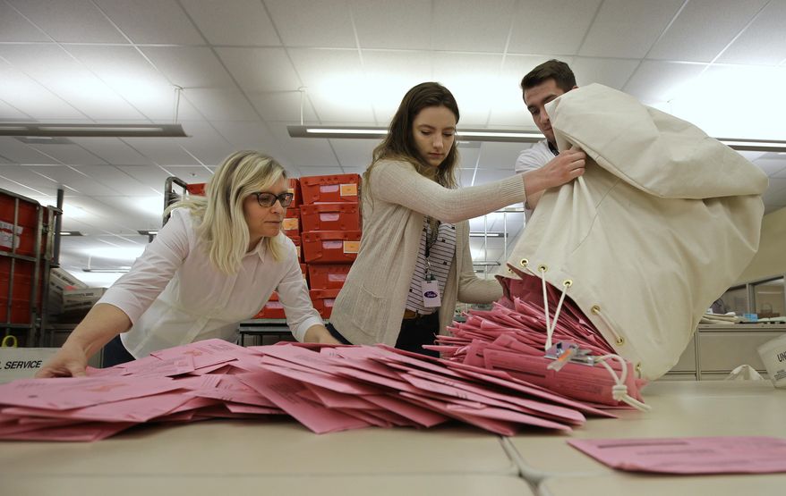 File - In this June 5, 2018, file photo, election workers Heidi McGettigan, left, Margaret Wohlford, center, and David Jensen, unload a bag of ballots brought in a from a polling precinct to the Sacramento County Registrar of Voters office in Sacramento, Calif. If control of the U.S. House comes down to any of the competitive congressional races in Washington state and California, the American public might have to wait a while to learn the outcome because of the way those states handle mail-in votes. (AP Photo/Rich Pedroncelli, File)
