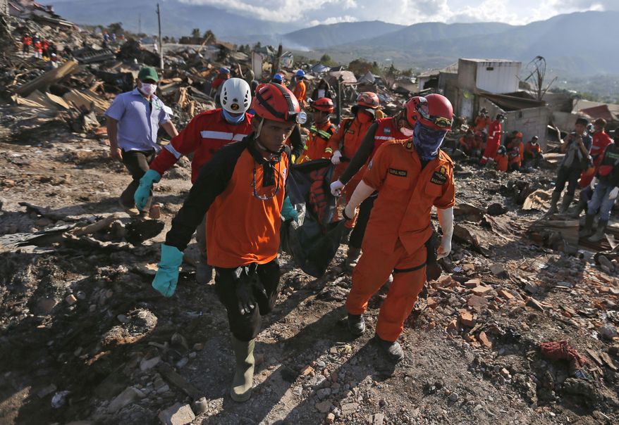 In this Monday, Oct. 8, 2018, file photo, rescuers remove the body of an earthquake victim from the devastated village of Balaroa in Palu, Central Sulawesi, Indonesia. (AP Photo/Dita Alangkara, File)