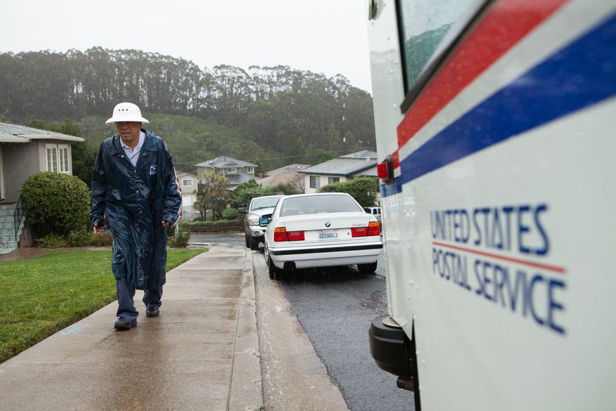 In this Dec. 11, 2014, file photo, Danny Joe delivers mail in the rain in San Bruno Calif. (AP Photo/Alex Washburn, File)