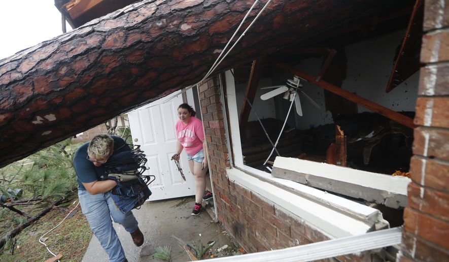 Megan Williams, left, and roommate Kaylee O'Brian take belongings from their destroyed home after several trees fell on the house during Hurricane Michael in Panama City, Fla., Wednesday, Oct. 10, 2018. (AP Photo/Gerald Herbert)