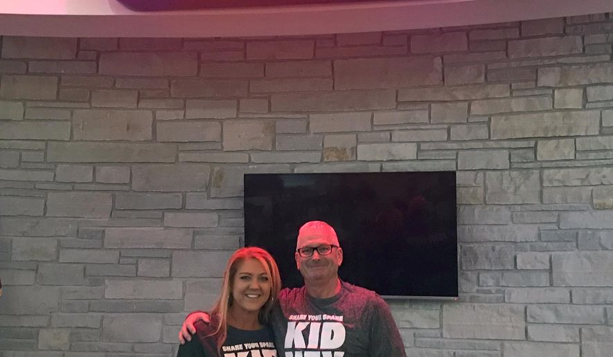 In this Sept. 25, 2018, photo, Nicole Braatz, left, and Paul Osterholm pose for a photo at Common Grounds, a coffeehouse in Fond du Lac, Wis. The two met at Common Grounds in 2001 when she was commissioned to make the sign they are standing below. He is now donating one of his kidneys to her. (Sarah Razner/The Reporter via AP)