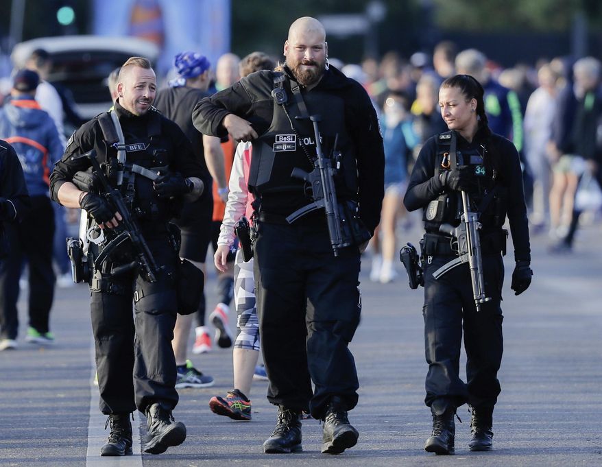FILE - In this Sept. 16, 2018 file photo three armed police officers patrol between runners prior to the 45th Berlin Marathon in Berlin, Germany. Berlin’s top security official says he’s decided to nix height requirements for police recruits in order to expand the pool of potential officers in the German capital, he’d decided that the minimum height requirements of 160 cm (5 feet, 3 inches) for women and 165 cm (5 feet, 5 inches) for men were archaic. (AP Photo/Markus Schreiber, file)