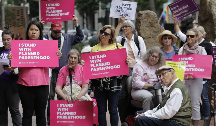 FILE - In this July 10, 2018 file photo, protesters hold signs supporting Planned Parenthood in Seattle, as they demonstrate against President Donald Trump and his choice of federal appeals Judge Brett Kavanaugh as his second nominee to the Supreme Court. On Wednesday, Oct. 10 Planned Parenthood unveiled a plan to protect access to abortion as widely as possible even if the Supreme Court moves to curtail women's right to undergo the procedure. (AP Photo/Ted S. Warren, File)