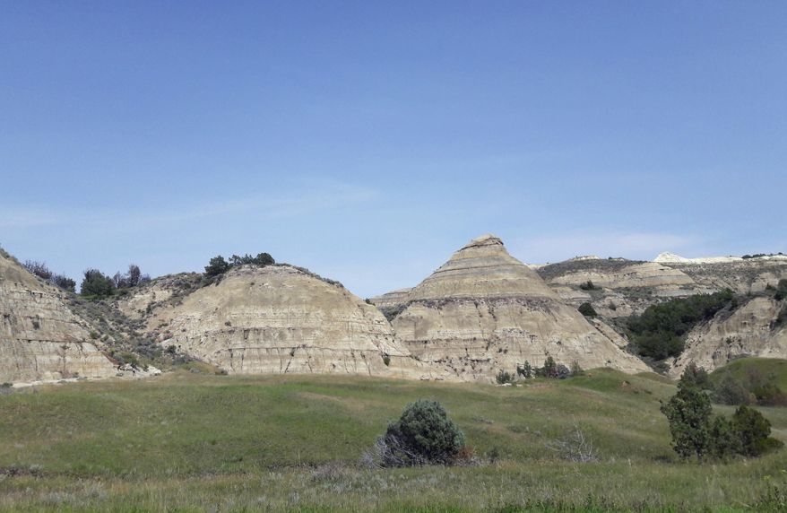 FILE - This Aug. 1, 2018, file photo, shows a view of the badlands landscape at Theodore Roosevelt National Park near Medora, N.D. North Dakota regulators won't order a company to stop work on an oil refinery near Theodore Roosevelt National Park so they can study the appropriateness of the site. The decision eliminates a potential big roadblock for the $800 million Davis Refinery. But it's based on a technicality in state law and is unlikely to end debate over whether the refinery is too close to the state's top tourist attraction. (AP Photo/Steve Karnowski, File)