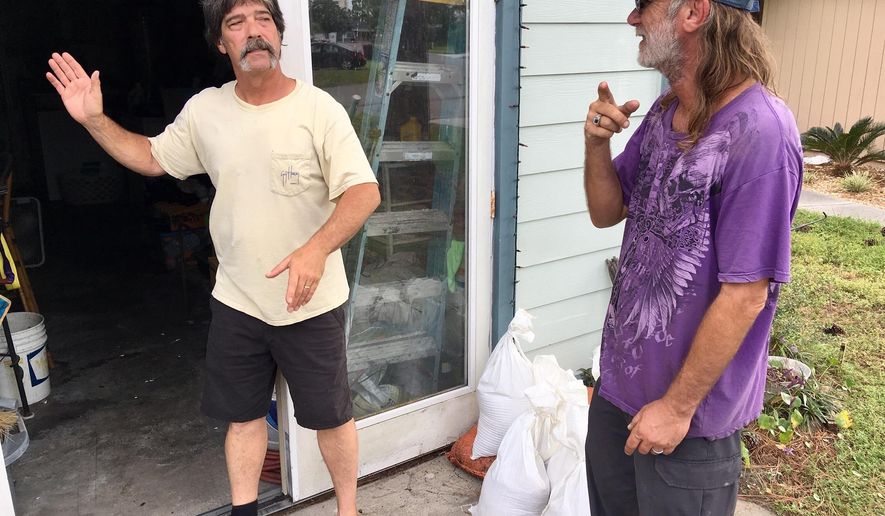 Dwight Williams, left, and Timothy Thomas discuss whether to evacuate their neighborhood in Panama City Beach, Fla., on Tuesday, Oct. 9, 2018. Thomas figures he and his wife will be safe from rising ocean water since they live in a second-story apartment. Others also aren’t leaving, and a bar along the beachfront road threw a hurricane party less than 2 miles away from Thomas’ home as Michael pushed toward shore Tuesday night. (AP Photo/Jay Reeves)