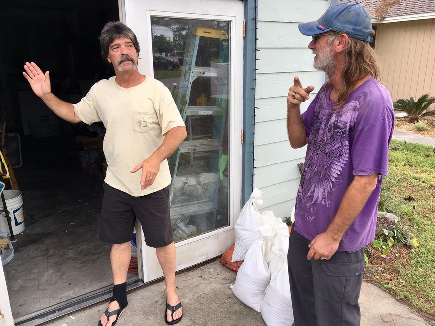 Dwight Williams, left, and Timothy Thomas discuss whether to evacuate their neighborhood in Panama City Beach, Fla., on Tuesday, Oct. 9, 2018. Thomas figures he and his wife will be safe from rising ocean water since they live in a second-story apartment. Others also aren’t leaving, and a bar along the beachfront road threw a hurricane party less than 2 miles away from Thomas’ home as Michael pushed toward shore Tuesday night. (AP Photo/Jay Reeves)