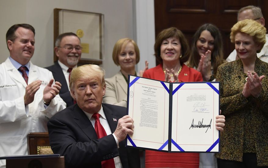 President Donald Trump holds up the 'Patient Right to Know Drug Prices Act' after signing it and the 'Know the Lowest Price Act of 2018,' during a ceremony in the Roosevelt Room of the White House in Washington, Wednesday, Oct. 10, 2018. These bills, which were sponsored by Sen. Susan Collins, R-Maine, in red, and Sen. Debbie Stabenow, D-Mich., right, help protect Medicare patients and those with private insurance from overpaying for prescription drugs by outlawing pharmacy "gag clauses." (AP Photo/Susan Walsh)