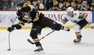 Pittsburgh Penguins&#39; Phil Kessel, left, snaps a shot as Vegas Golden Knights&#39; Colin Miller (6) defends during the second period of an NHL hockey game Thursday, Oct. 11, 2018, in Pittsburgh. Kessel scored on the play, his second of the period and third of the game. (AP Photo/Keith Srakocic)