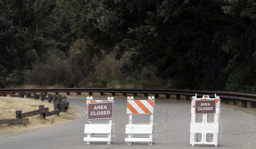 Signs indicate a road closure at the Malibu Creek State Park Thursday, Oct. 11, 2018, in Calabasas, Calif. Investigators will use ballistic testing to determine if a rifle carried by a burglary suspect was used in the killing of a camper at the California wilderness park. Authorities say 42-year-old Anthony Rauda had the gun and was dressed in black when he was arrested Wednesday after a search of a rugged canyon area near Malibu. (AP Photo/Marcio Jose Sanchez)
