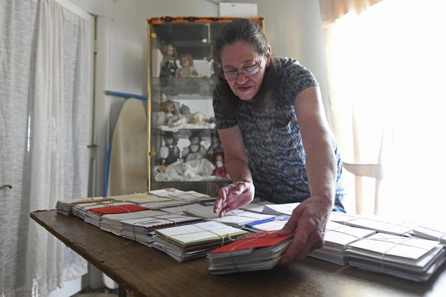 In this Sept. 19, 2018 photo, Connie Wietrzykowski tallies the 4,500 Christmas cards she's written for U.S. troops during commercial breaks while watching television at home in Bradley, Ill., After work during network breaks, she has a mission, writing the cards for U.S. servicemen and women around the country and overseas. Meanwhile, husband Tom Vince Wietrzykowski cooks and washes dishes. (Tiffany Blanchette/The Daily Journal via AP)