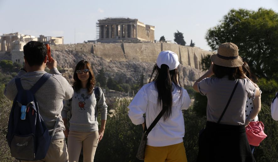 Tourists from Taiwan take photographs with the closed Acropolis ancient site in the background in Athens, Thursday, Oct. 11, 2018 during a 24-hour strike called by a Greek union representing staff at the country&#x27;s ancient site. The union accused the Greek government of failing to list publicly-owned properties that have been transferred to a powerful privatization fund created during the country&#x27;s international bailouts. (AP Photo/Thanassis Stavrakis)