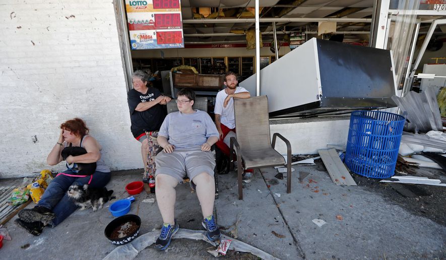 Dawn Vickers, left, her mother Patsy Vickers, son Ryder Vickers, and friend Robert Brock, right, who rode out Hurricane Michael in their now-destroyed home, sit in front of a damaged convenience store with nowhere to go, in Michael&#x27;s aftermath, in Mexico Beach, Fla., Thursday, Oct. 11, 2018. Their house floated away from its foundation in the storm and they escaped the water by wading through a window. (AP Photo/Gerald Herbert)