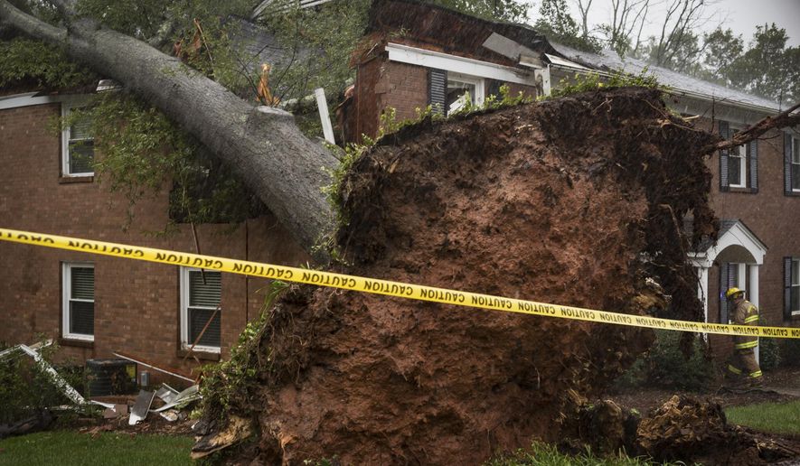 A Winston-Salem firefighter walks toward an apartment building which was struck by a toppled tree Thursday, Oct. 11, 2018, after the remnants of Hurricane Michael passed through Winston-Salem, N.C. (Allison Lee Isley/The Winston-Salem Journal via AP)