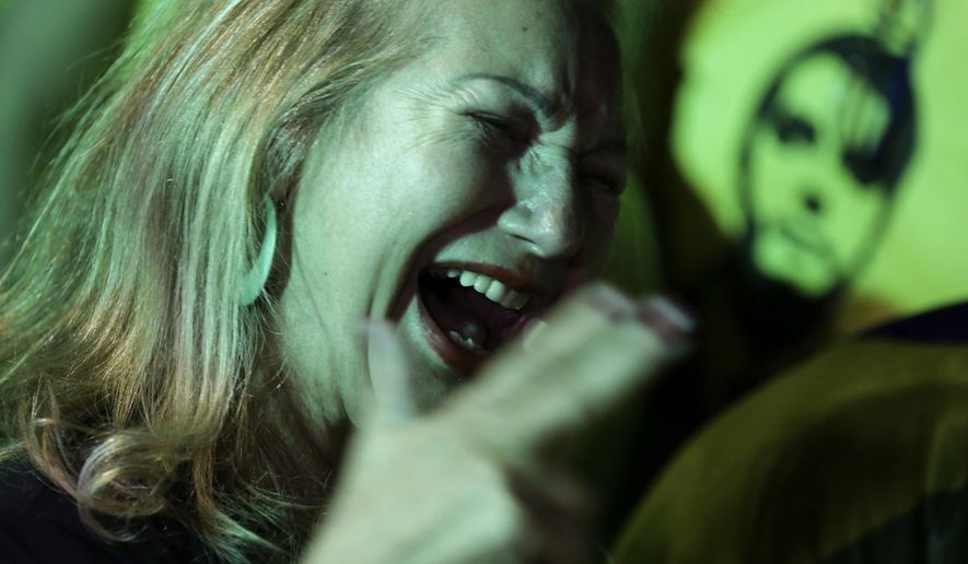 In this Sunday, Oct. 7, 2018 photo, a supporter of presidential frontrunner Jair Bolsonaro celebrates as she waits for election results, in front of the National Congress Palace, in Brasilia, Brazil. Brazilians appear on the cusp of handing the presidency to Bolsonaro, a brash former army captain who has reminisced fondly about dictatorship, pledged to jail corrupt politicians and promised an all-out war on the drugs and crime that plague South America's largest nation. (AP Photo/Eraldo Peres)