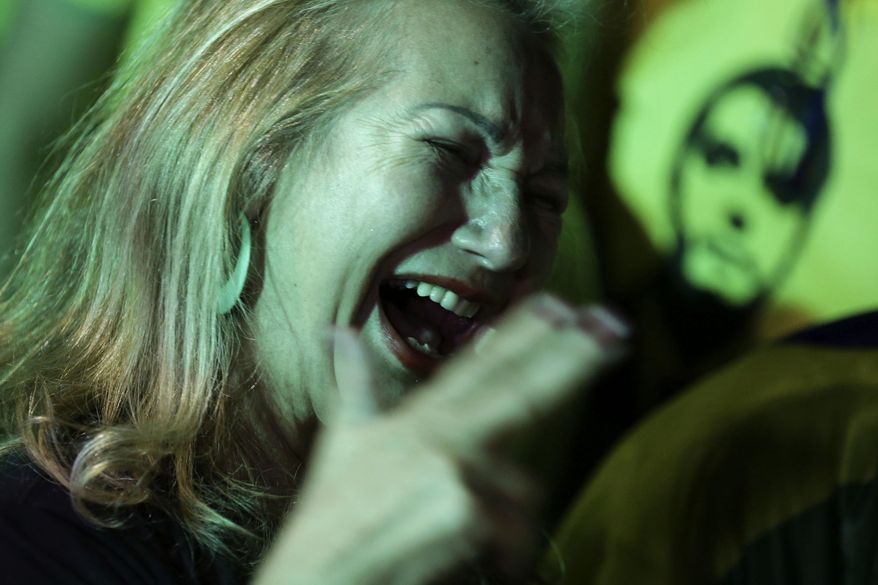 In this Sunday, Oct. 7, 2018 photo, a supporter of presidential frontrunner Jair Bolsonaro celebrates as she waits for election results, in front of the National Congress Palace, in Brasilia, Brazil. Brazilians appear on the cusp of handing the presidency to Bolsonaro, a brash former army captain who has reminisced fondly about dictatorship, pledged to jail corrupt politicians and promised an all-out war on the drugs and crime that plague South America's largest nation. (AP Photo/Eraldo Peres)