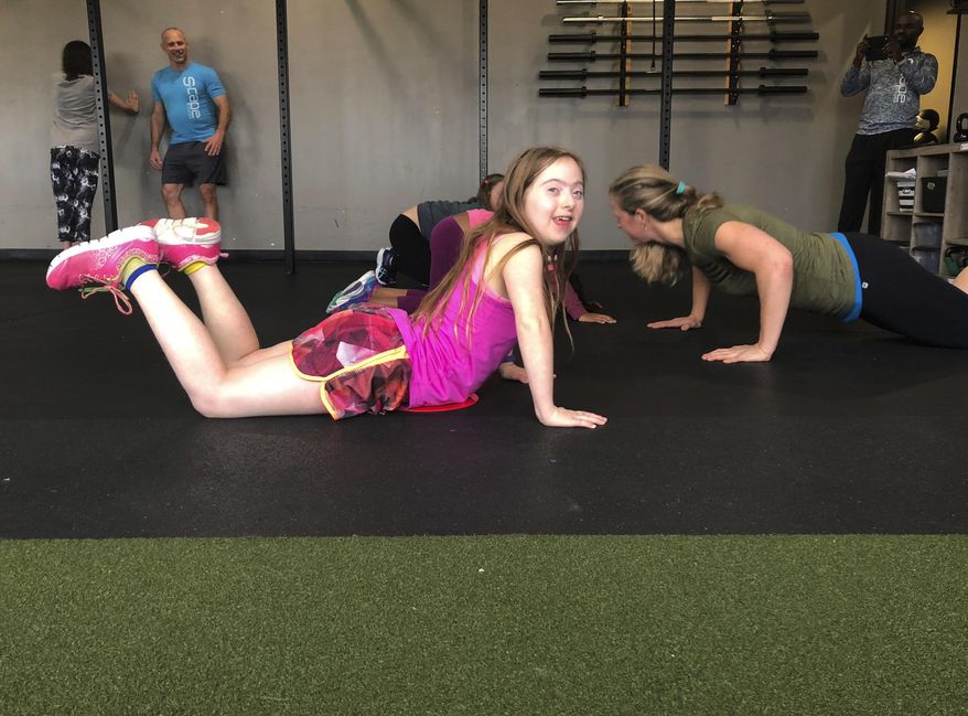 In this Sept. 30, 2018, photo, Cadie Albin does a pushup during a fitness class at S-Cape Fitness in Omaha, Neb. The class is open for kids and teens with any kind of disability. (Kelsey Stewart/Omaha World-Herald via AP)