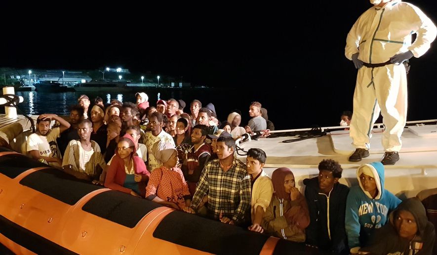 Migrants prepare to disembark from a dinghy boat upon their arrival at the Lampedusa harbor, southern Italy, Saturday, Oct. 13, 2018 after an Italian coast guard boat rescued them off the coast of the tiny Lampedusa island. (Elio Desiderio/ANSA via AP)