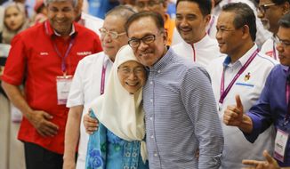 Malaysia&#39;s politician Anwar Ibrahim, right, hug his wife while Deputy Prime Minister Malaysia Wan Azizah Ismail celebrates after winning the by election in the southern coastal town in Port Dickson, Saturday, Oct. 13, 2018. Malaysian politician Anwar Ibrahim won a parliamentary seat and returns to active politics as he prepare for his eventual takeover from Prime Minister Mahathir Mohamad. (AP Photo/Vincent Thian)